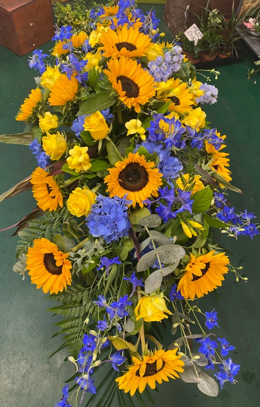 Bright yellow and blue casket spray