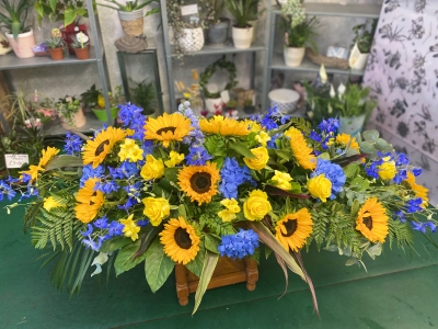 Bright yellow and blue casket spray